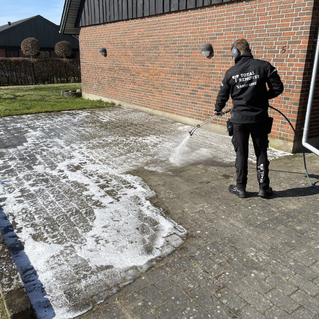 Total-Remove teknikker udfører algebehandling af flisebelægning ved murstenshus