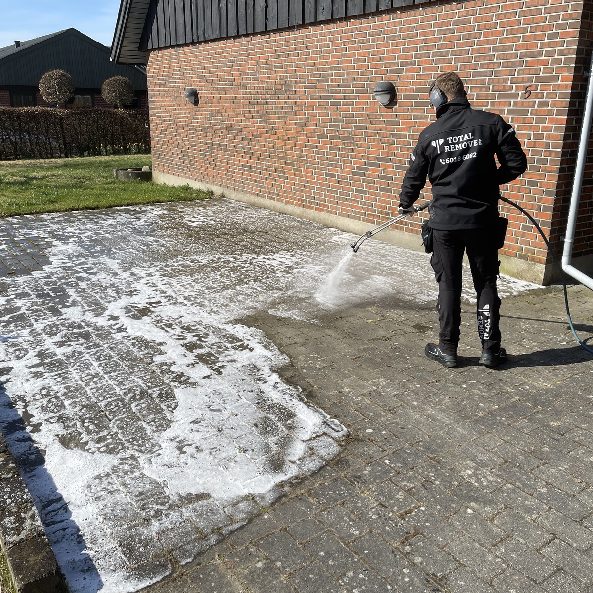 Total-Remove teknikker udfører algebehandling af flisebelægning ved murstenshus